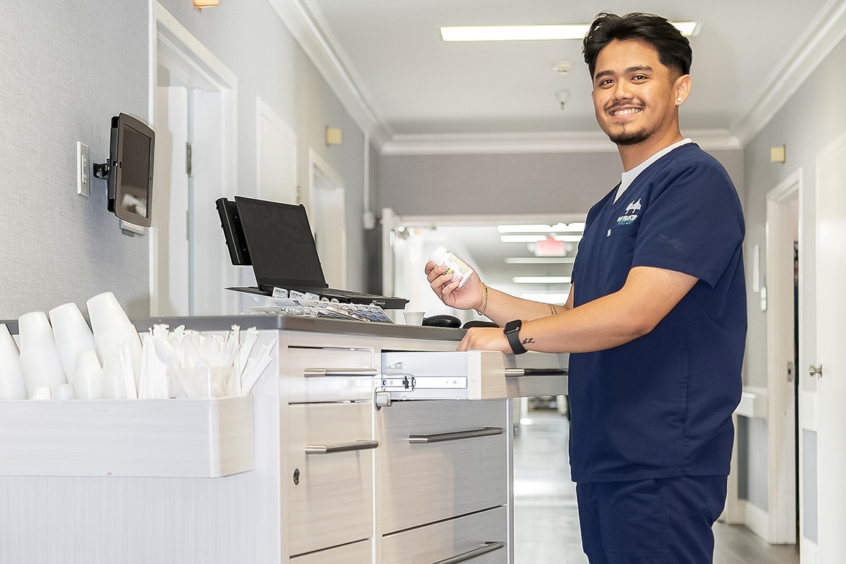 Smiling nurse at a nurses cart in the hallway