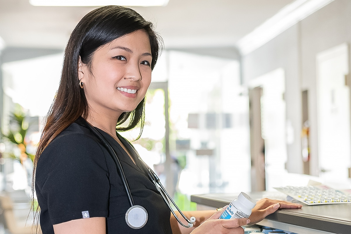 Smiling nurse at a nurses cart in the hallway